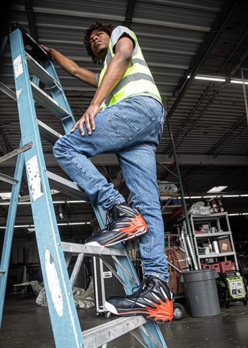 Worker wearing Reebok work shoes climbing ladder